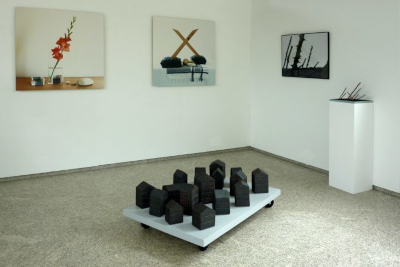 Escultura de Caxigueiro consistente en varias pilas de libros de cerámica escura. Están colocados no xardín arrodeados de fentos